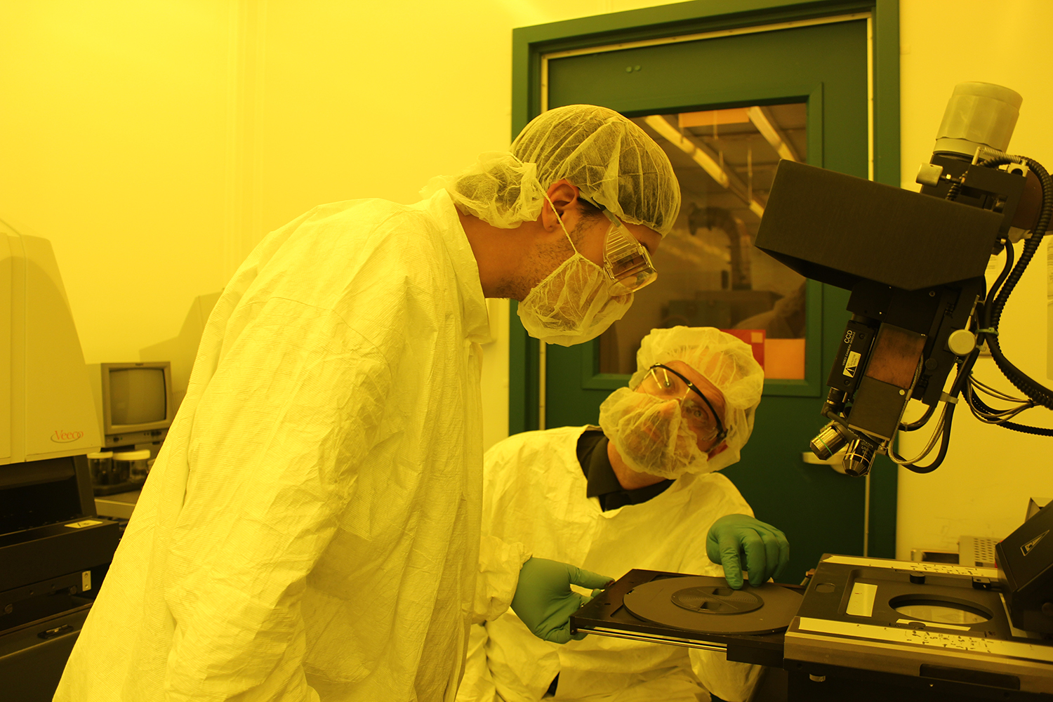 Photo: Matt Pleil works with a student in the MTTC cleanroom at UNM.