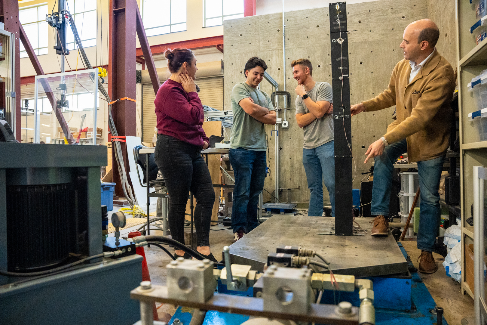 photo: Associate Professor Fernando Moreu (right) shows Gabriella Gallegos, a 2nd year Civil Engineering master’s student, Michael Carl, an undergraduate student in the Department of Computer Science, and Wyatt Saeger, a 2nd year Civil Engineering master’s student, the hydraulic actuator, which helps his lab study earthquakes and structural dynamics.